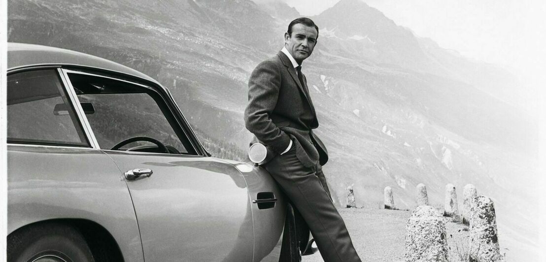 Sean Connery lehnt in der Rolle des James Bond an einem Aston Martin