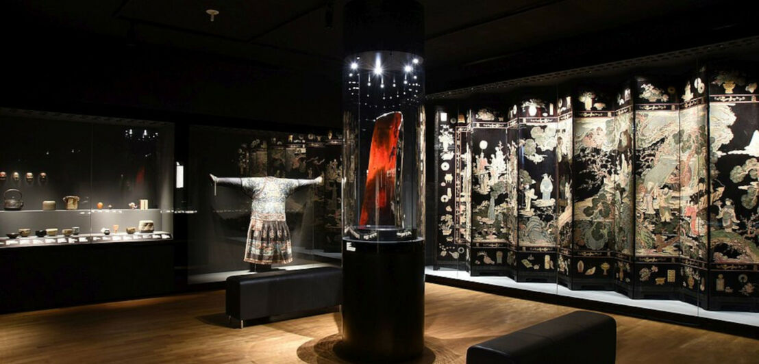 Ein ausgeleuchteter Museumsraum mit mehreren asiatischen Exponaten