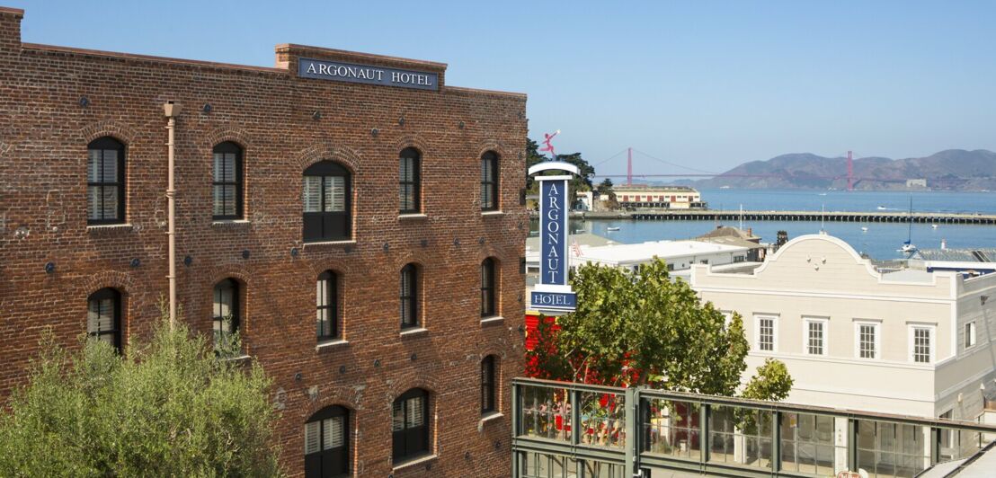 Backsteingebäude des Argonaut Hotels an der Bucht von San Francisco, im Hintergrund die Golden Gate Bridge
