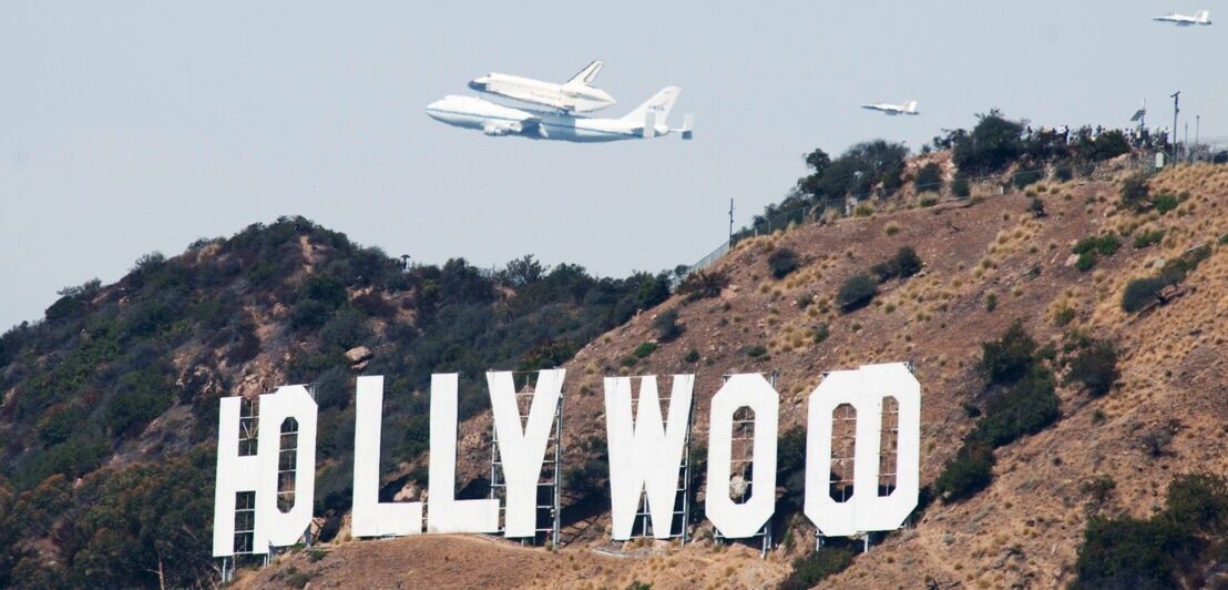 Eine Boing 747 fliegt mit dem Space Shuttle Endeavour auf dem Rücken über dem Hollywood-Schild