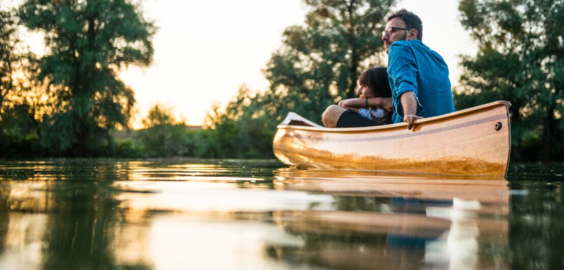 Ein Paar treibt in einem Kanu bei Sonnenuntergang auf einem See.