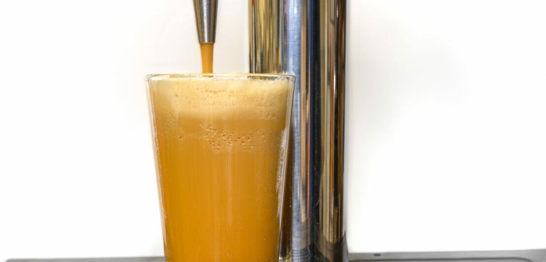 Nitro Cold Brew Kaffee, der in ein klares Glas mit feinen Stickstoffblasen und einer glatten Textur auf einem Fasskaffeespender gegossen wird