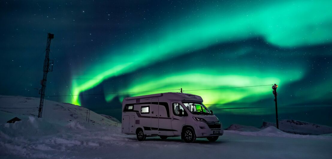 Ein Wohnmobil steht unter Polarlichtern