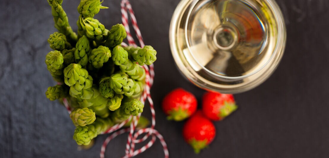 Ein Bund grüner Spargel mit Weißwein und Erdbeeren