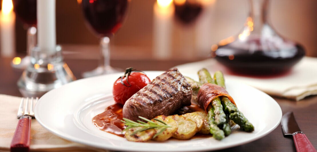 Ein Teller mit Steak, grünem Spargel und Rotwein