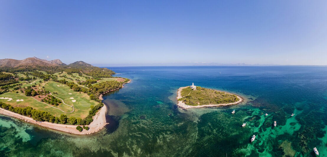 Blick auf eine Golfanlage am Meer und die Alcanada-Insel auf Mallorca