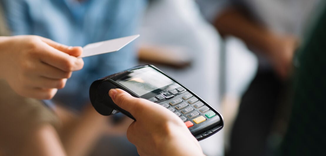 Eine Person bezahlt kontaktlos mit ihrer Kreditkarte. 