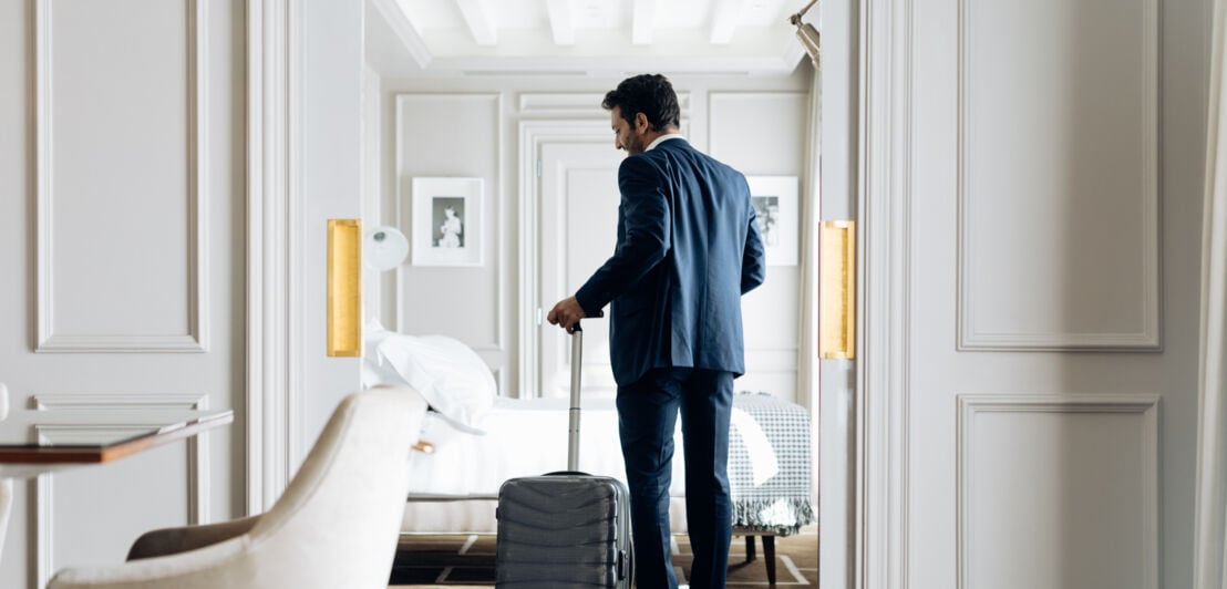 Ein Geschäftsmann mit Trolley in einem eleganten Hotelzimmer