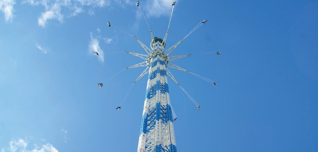 Ein blau weißes Kettenkarussell vor blauem Himmel