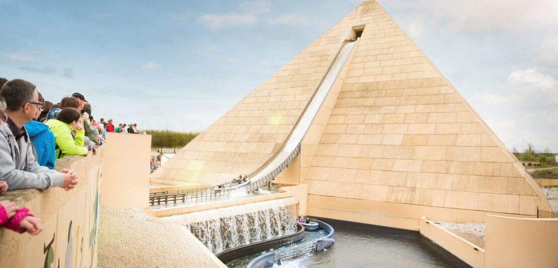 Einige Menschen schauen auf eine große Pyramide mit einem Wasserfall