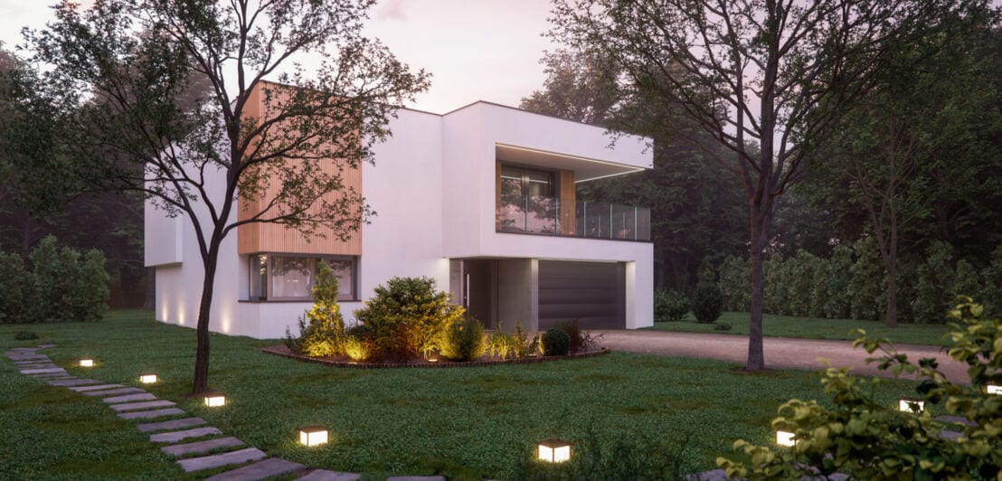 Ein modernes, kubistisches Haus mit Garten- und Wegbeleuchtung in der Abenddämmerung