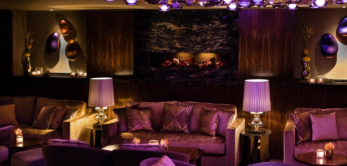 Gemütlich eingerichteter Lounge-Bereich mit Sofas und lilafarbener Beleuchtung