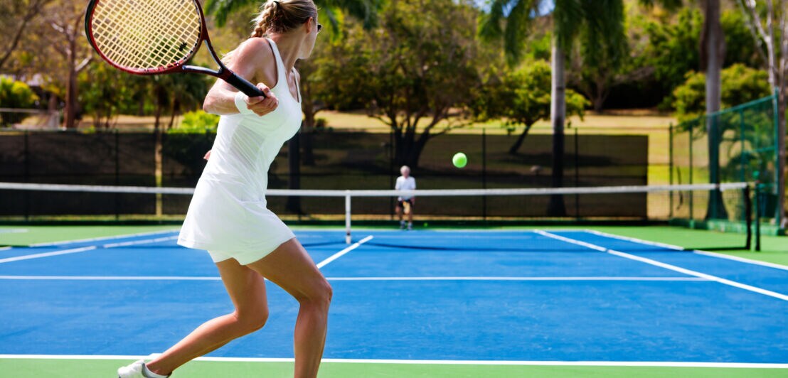 Zwei Personen, die Tennis in einer tropischen Umgebung spielen