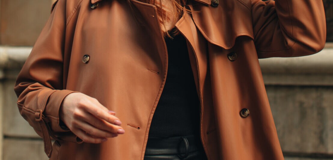 Nahaufnahme eines braunen Trenchcoats aus Leder an einer Frau 
