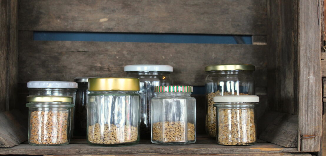 Unterschiedliche Getreidesorten, abgefüllt in Gläsern in einem Holzregal