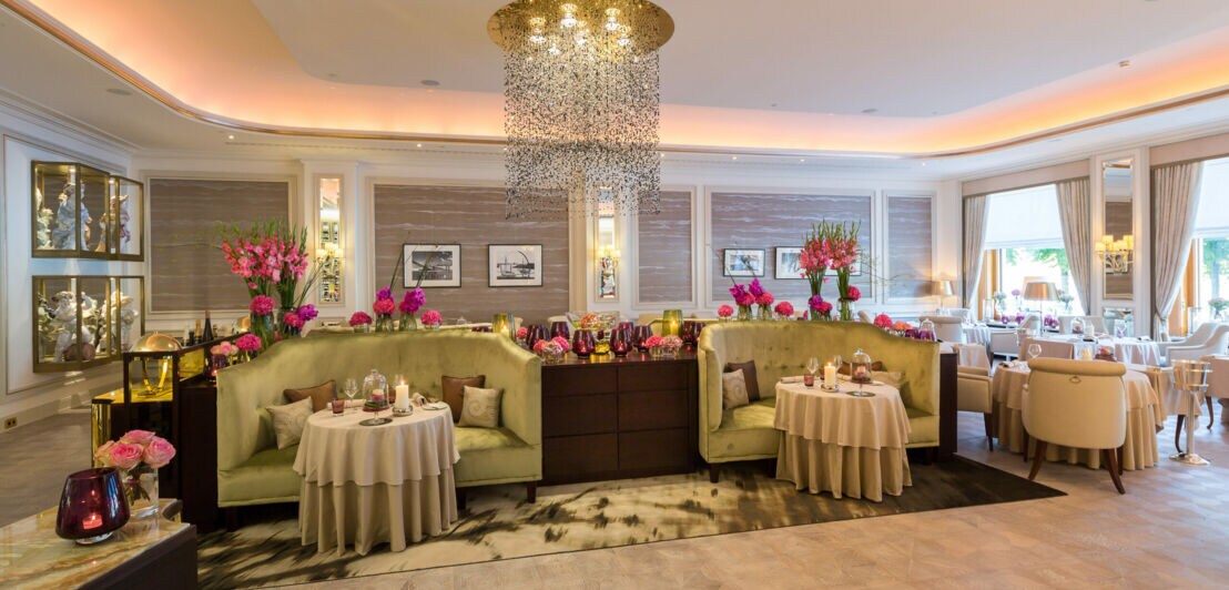 Luxuriöses Interieur des Drei-Sterne-Restaurants Haerlin mit kleinen gedeckten Tischen vor gepolsterten Sofas.