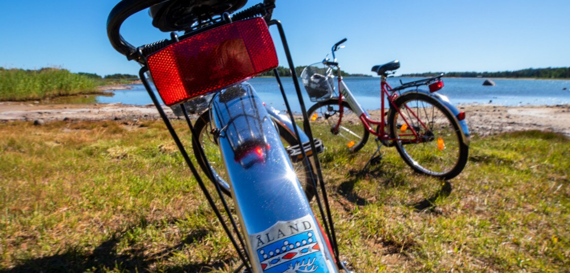 Zwei Fahrräder auf einer Wiese am See, Nahansicht eines Aufklebers auf dem Schutzblech