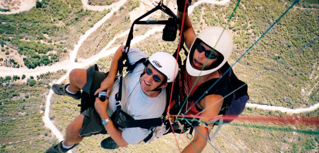 Zwei fröhliche Männer im Fallschirm genießen die Aussicht
