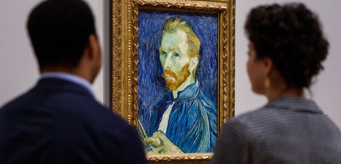 Zwei Personen betrachten ein Selbstporträt von Vincent van Gogh in einem Museum