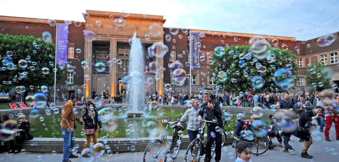 Menschen vor einem Museum mit vielen Seifenblasen