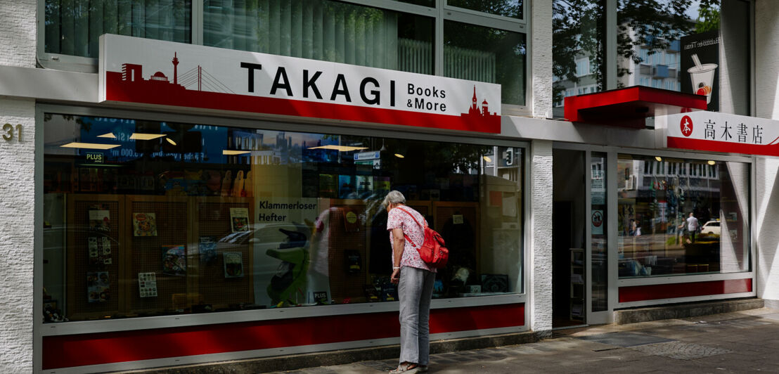 Eine Frau steht vor dem Schaufenster einer japanischen Buchhandlung