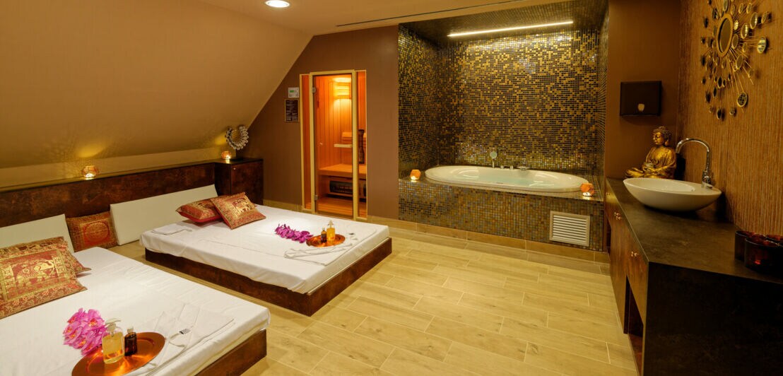 Wellnessbereich mit Badewanne, Betten und goldenen Dekoelementen