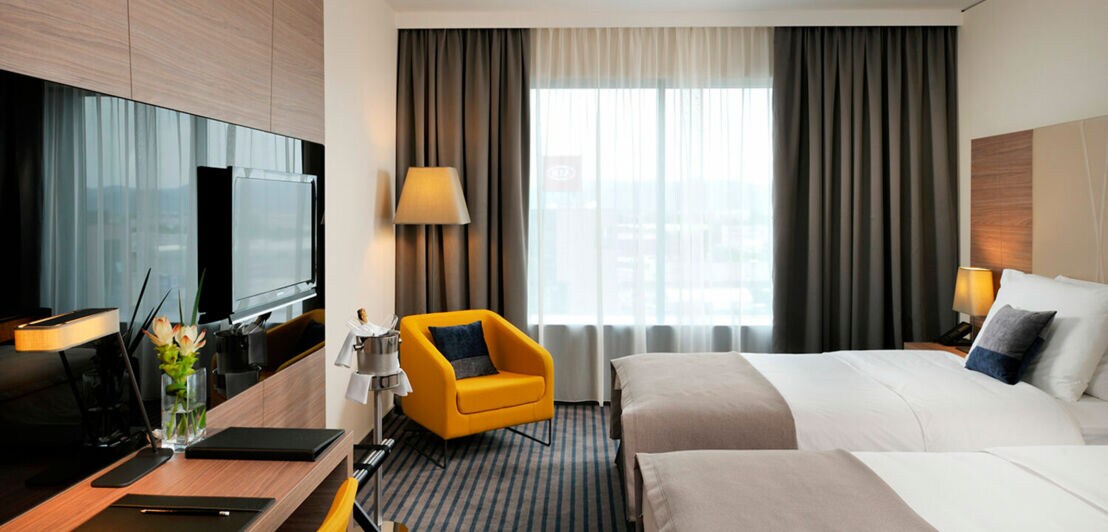 Hotelzimmer in Brauntönen mit Bett, Sofa und Tisch