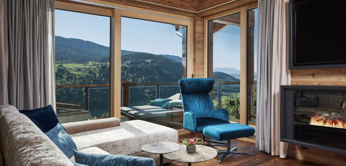 Innenansicht eines Hotelzimmers mit Panoramafenster und Ausblick auf Berge