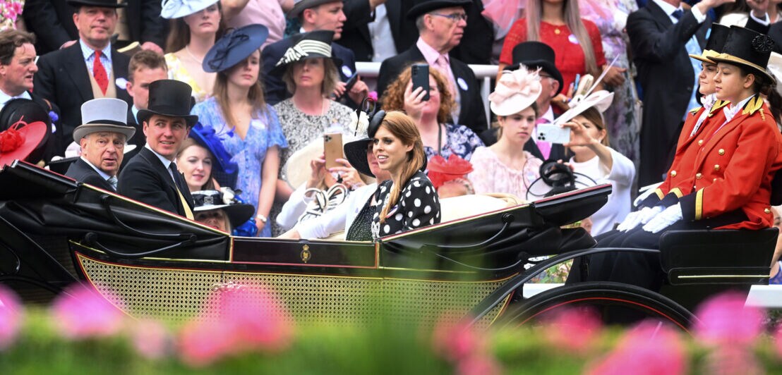 Mitglieder der britischen Königsfamilie fahren beim Royal Ascot Pferderennen in einer Kutsche an einer Zuschauertribüne vorbei
