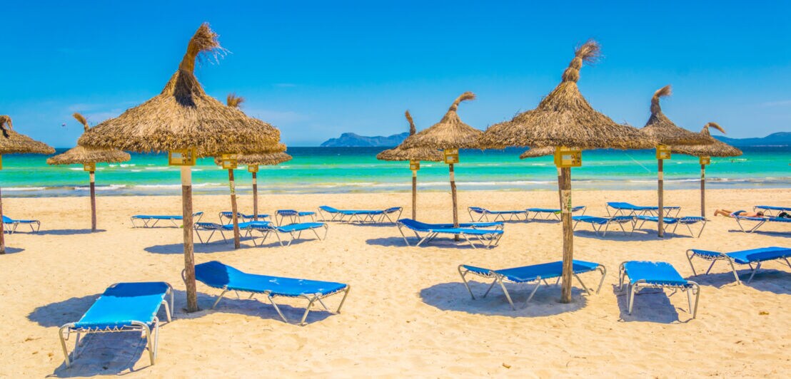 Blaue Sonnenliegen und Sonnenschirmen am Playa de Muro
