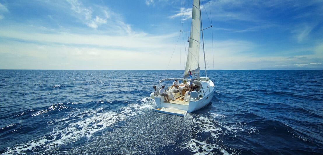 Ein Segelboot fährt auf dem offenen Meer und hinterlässt Schaumkronen