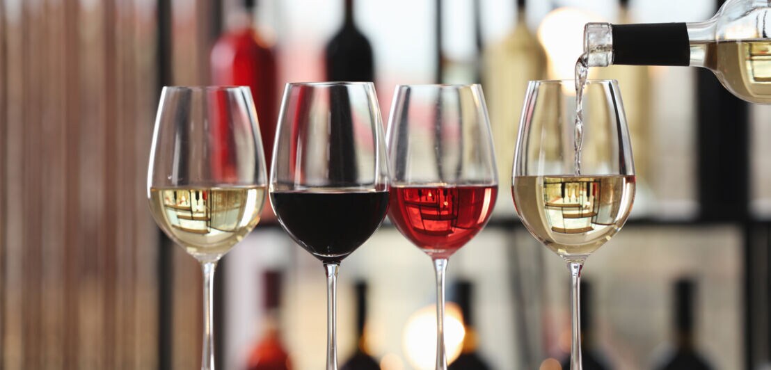 Vier Gläser nebeneinander, gefüllt mit Rot- und Weißwein sowie Rosé