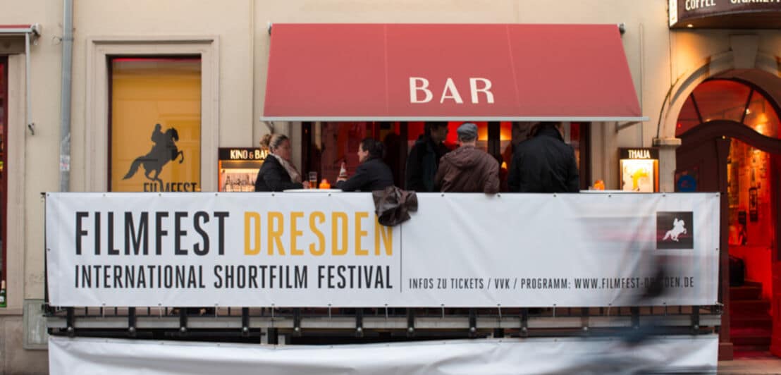 Ein Plakat für das Filmfest Dresden vor einer Bar