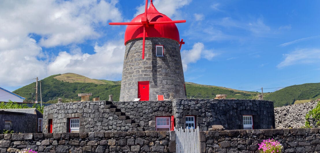 Eine Windmühle aus Stein mit rotem Dach
