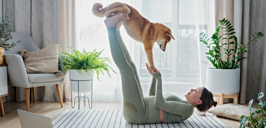 Eine junge Frau macht Yoga mit Hund