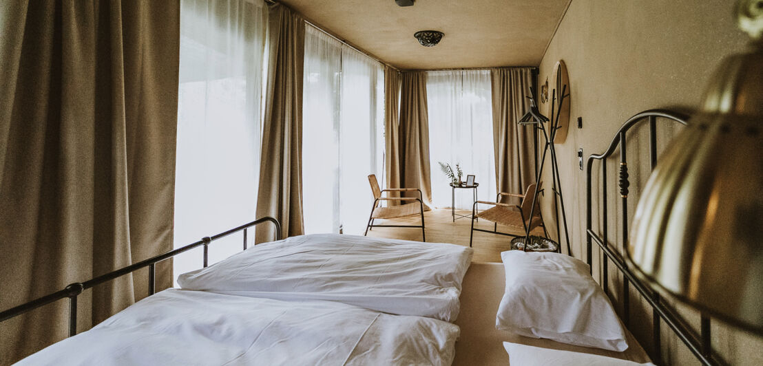 Blick in ein Hotelzimmer mit Doppelbett und zwei Stühlen.