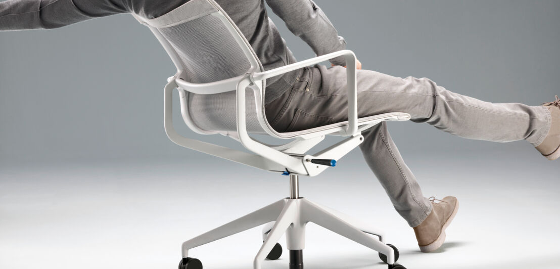 Rückansicht eines Mannes auf einem modernen, weißen Bürostuhl auf Rollen mit flexibler Rückenlehne