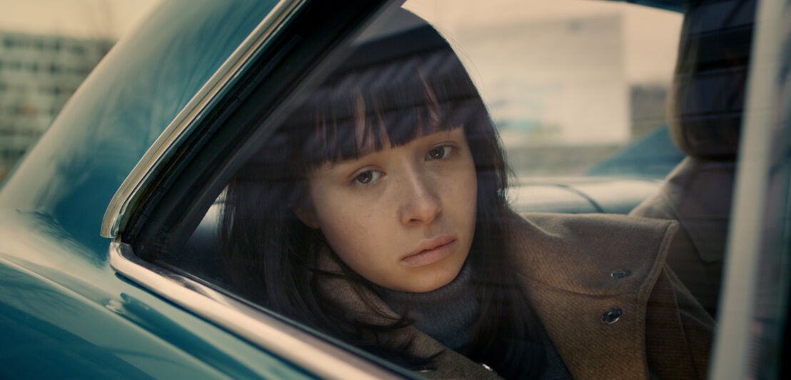 Filmszene aus dem Film The Ordinaries, in der ein Mädchen aus einem Autofenster schaut