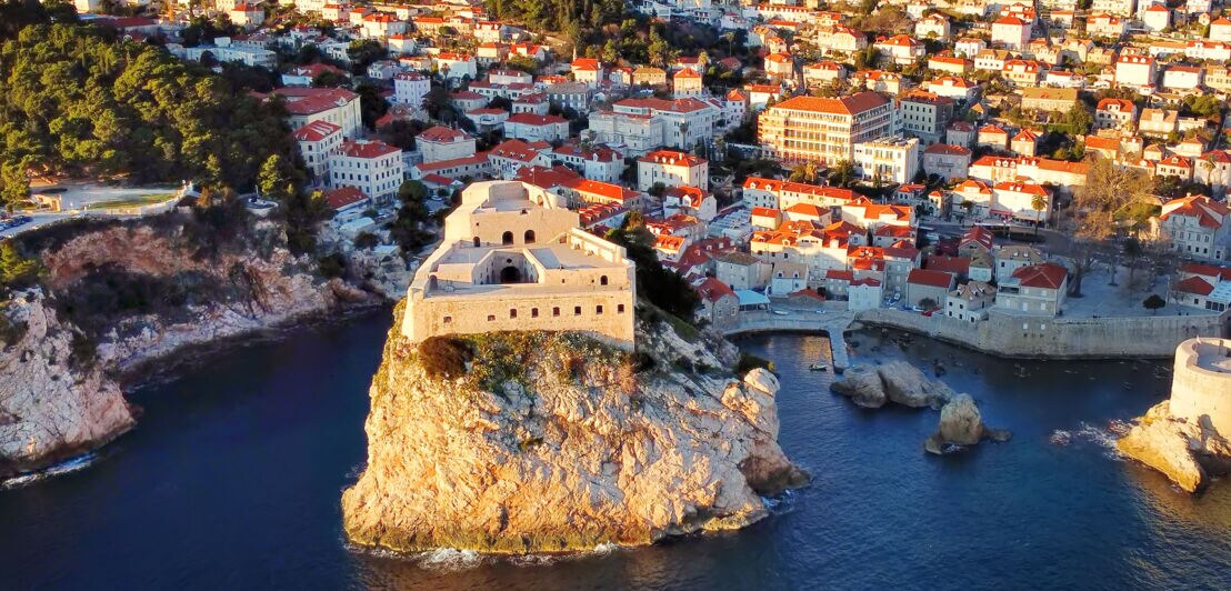 Luftaufnahme einer Festung auf einem hohen Felsen im Wasser vor der Stadt Dubrovnik