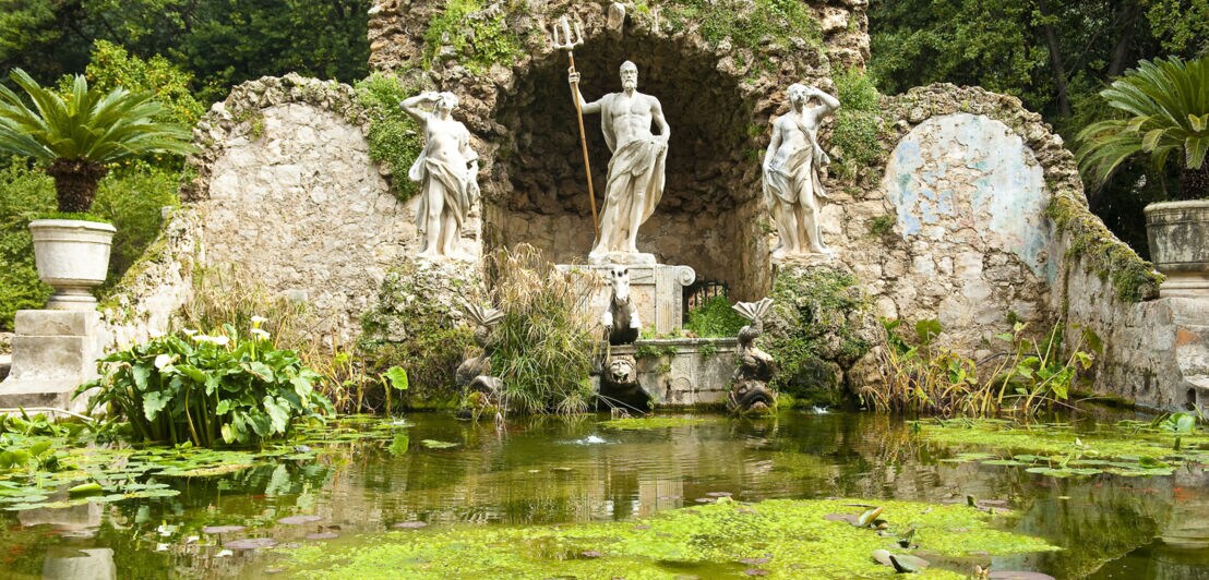 Ein Teich mit einer Neptun-Statue in einem botanischen Garten