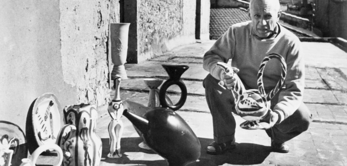 Schwarzweißfoto von Pablo Picasso mit Keramikarbeiten vor seinem Studio in Vallauris