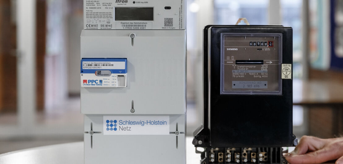 Ein digitaler Stromzähler mit Smart-Meter-Gateway steht neben einem herkömmlichen analogen Zähler