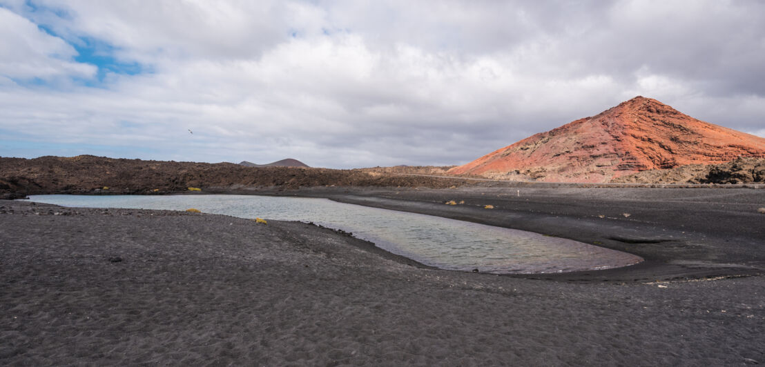 Schwarzer Sand und der Vulkankrater Montana Bermeja auf Lanzarote