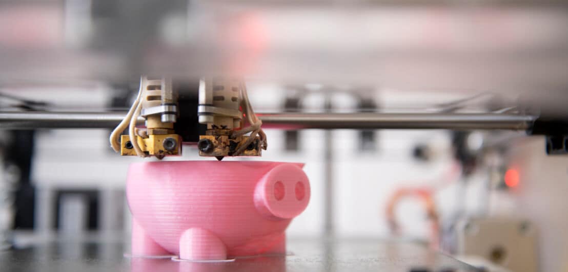 Ein 3D-Modell in Schweineform aus rosa Kunststoff wird in einem 3D-Drucker erstellt