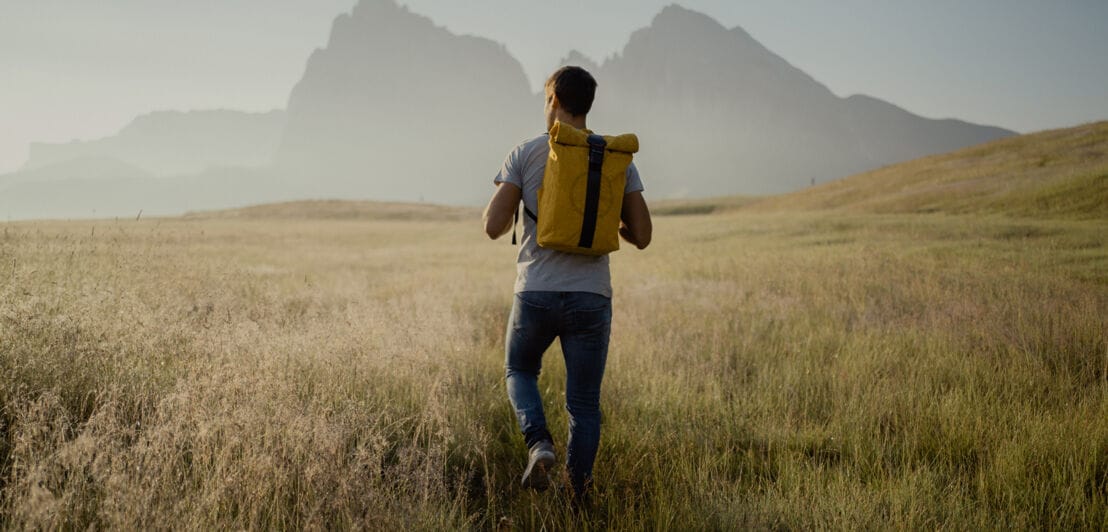 Ein Mann trägt einen Rucksack von Airpaq auf dem Rücken und geht durch die Natur.