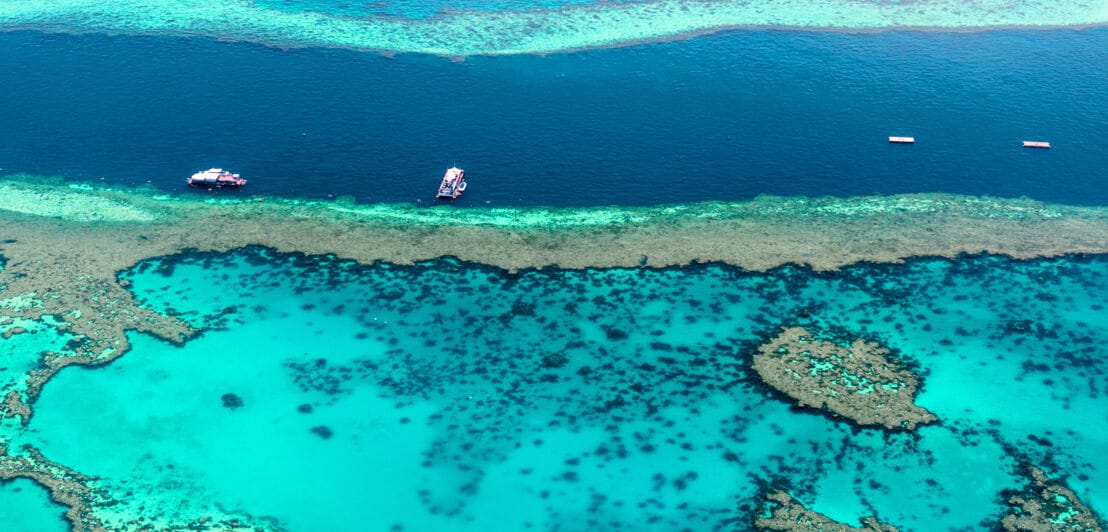 Türkisblaue Wasseroberfläche des Great Barrier Reef mit Booten aus der Luft