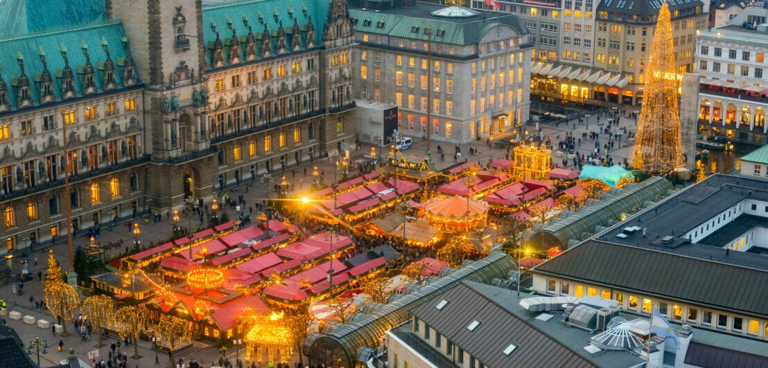 Luftaufnahme eines Weihnachtsmarktes vor dem Hamburger Rathaus bei Dämmerung
