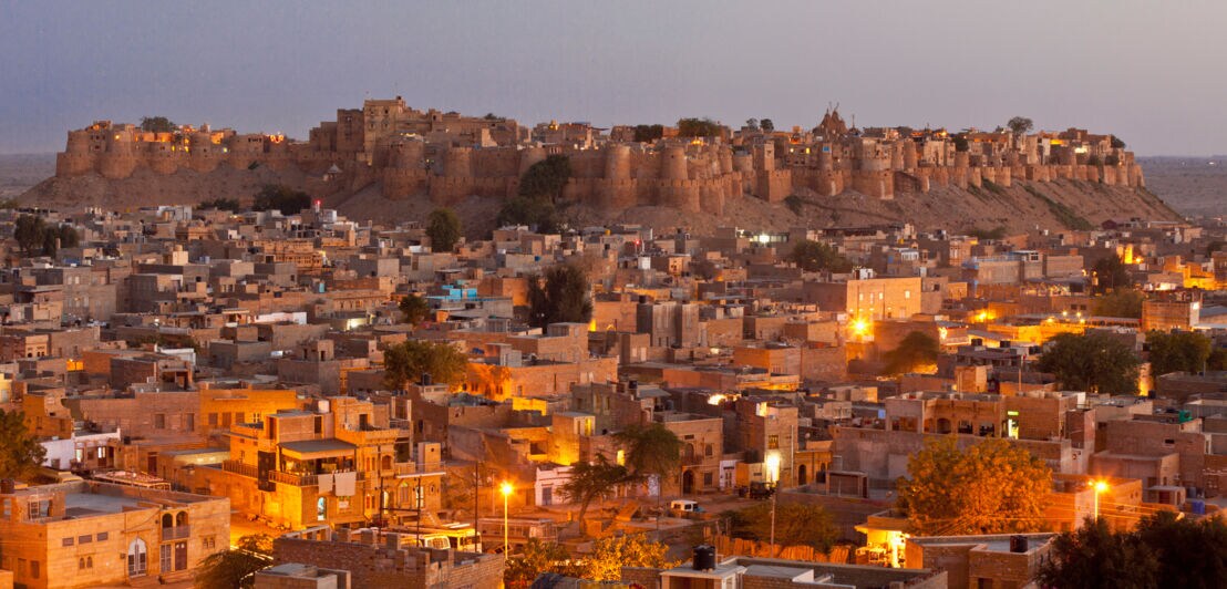 Blick auf eine in der Abenddämmerung beleuchteten indischen Stadt.