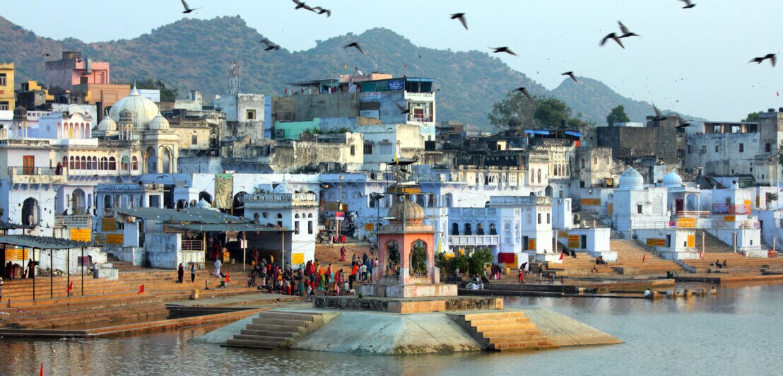 Blick auf eine indische Stadt mit einem See im Vordergrund. 