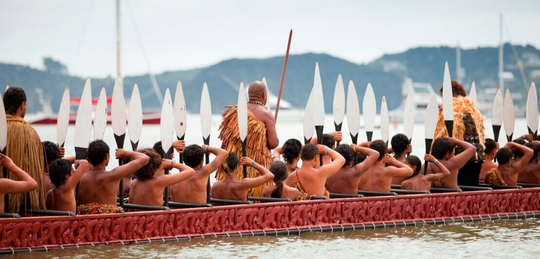 Menschen in traditioneller Kleidung auf einem Boot.